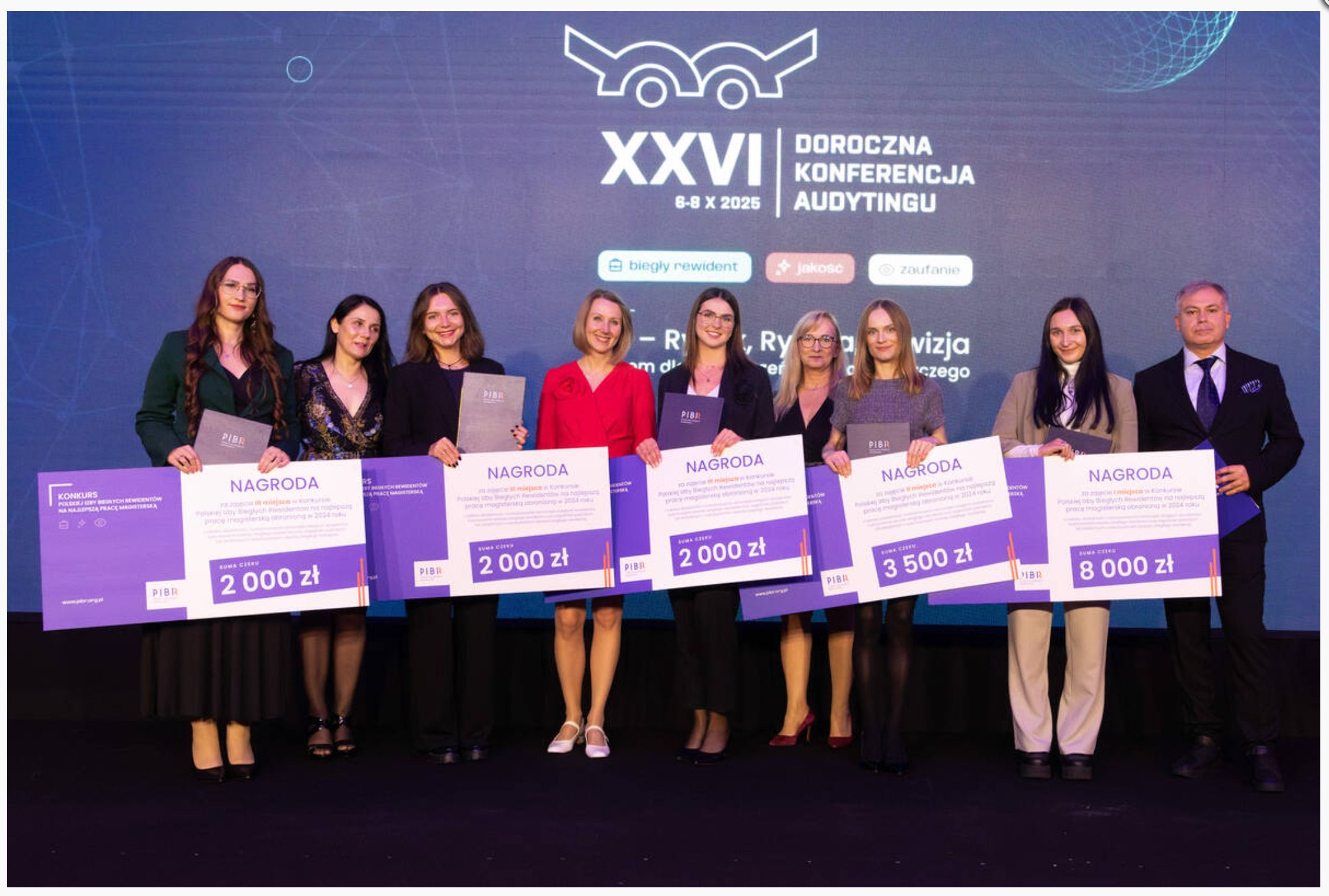 Na zdjęciu przedstawiona jest grupa ośmiu osób stojących w rzędzie. Są to kobiety i mężczyzna, wszyscy elegancko ubrani. W tle widać ciemne tło z logo i napisem "Doroczna Konferencja Audytingu", co sugeruje, że to wydarzenie związane z audytem. Wszyscy trzymają duże tablice z napisem "Nagroda" i kwotami od 2000 zł do 8000 zł, co wskazuje, że są to uczestnicy lub laureaci konkursu związany z audytem. Panuje atmosfera radości i triumfu, sugerująca, że osoby te są zadowolone z otrzymanych nagród. Miejsce wygląda jak scena konferencyjna. Czas dnia czy sezon nie jest możliwy do ustalenia na podstawie samego zdjęcia.
